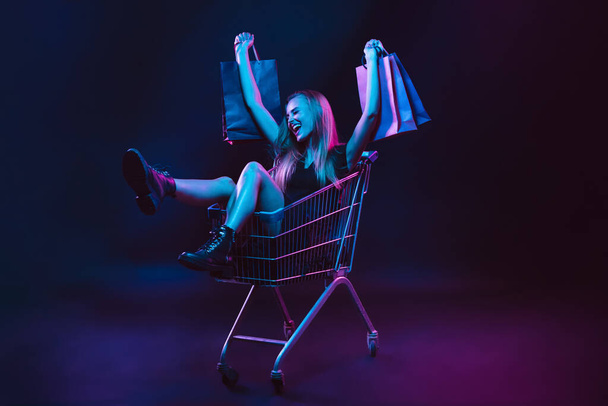 Portrait of young woman in neon light on dark backgound. The human emotions, black friday, cyber monday, purchases, sales, finance concept. - Foto, immagini