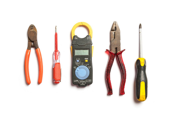 Vue du dessus des outils de travail pour électricien, marteau, tournevis, pince, perceuse électrique, mesure, sur fond blanc. - Photo, image
