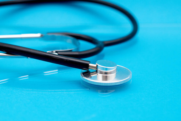 Stethoscoop met reflectie op blauwe achtergrond. Close-up van fonendoscoop. Concept van de medische gezondheidszorg. - Foto, afbeelding