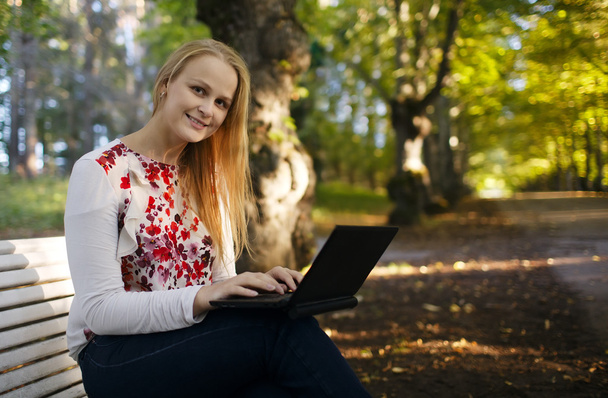 Young woman using her laptop in the park - Photo, Image