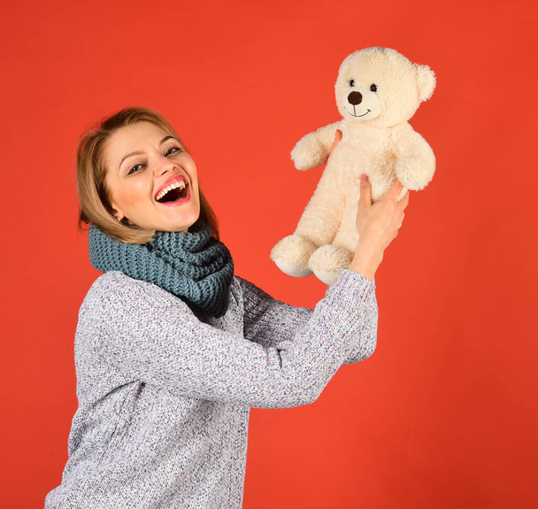 Woman holds teddy bear on red. Lady with blond hair - Fotó, kép