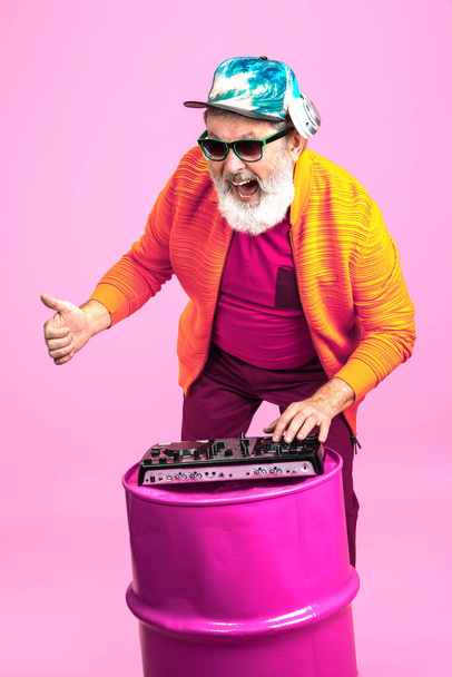 Senior hipster man wearing eyeglasses posing on pink background. Tech and joyful elderly lifestyle concept - Фото, зображення