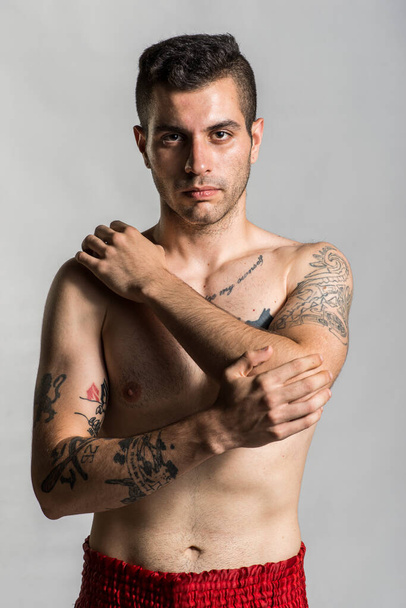 Молодий чоловік позує з татуюваннями в студійному знімку, як поганий хлопчик
. - Фото, зображення