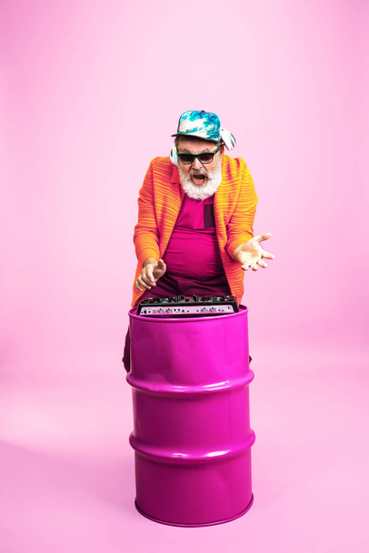 Senior hipster man wearing eyeglasses posing on pink background. Tech and joyful elderly lifestyle concept - Foto, Imagen