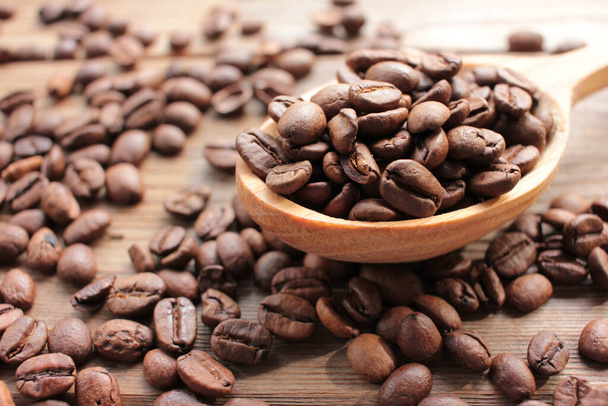 Свіжообсмажені кавові зерна в дерев'яній ложці на фоні дерева. русичний стиль
 - Фото, зображення