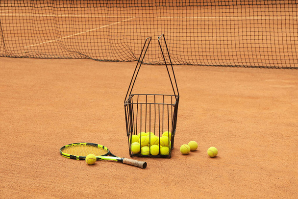 Raquete e cesta com bolas na quadra de barro - Foto, Imagem