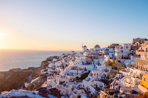 サントリーニ島の夕日ギリシャ,日没の間に教会や風車と美しい白塗りの村Oia - 写真・画像