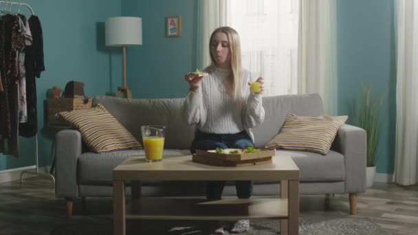 Ragazza in giacca bianca sta mangiando pizza e bere succo d'arancia - Filmati, video