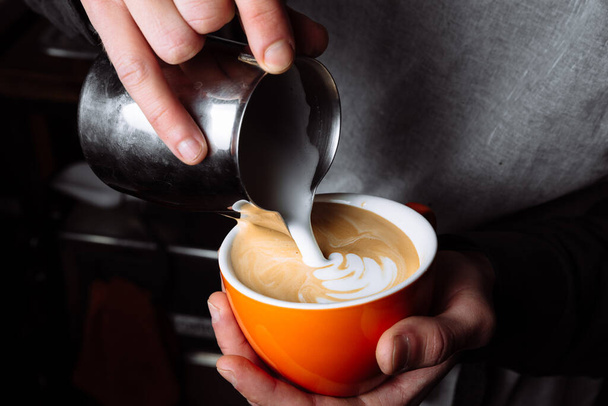 Kahveci elleri, sütlü kahve yapmak için kahve bardağına ılık süt koyuyor. Kapat. - Fotoğraf, Görsel