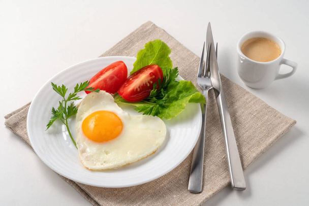 Food poster - Healthy and hearty breakfast. Close-up of a fried eggs, tomato, herbs and espresso coffee. Served on a white table with a linen napkin and cutlery. Meet my favorite fried egg: the crispy olive oil fried egg. These fried eggs have golden - Фото, зображення