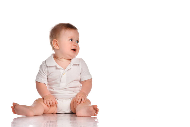 Intrigued baby in a white bodysuit looks to the side on a white background. - Foto, imagen