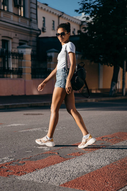 fiatal fekete bőrű turista lány sétál az utcán hátizsákkal. - Fotó, kép