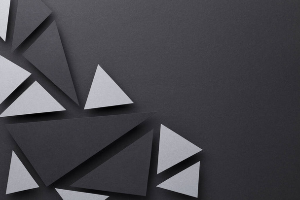 Abstract composition over black paper background with gray and black triangular shapes. Minimal style. Copy space. Top view - Фото, изображение