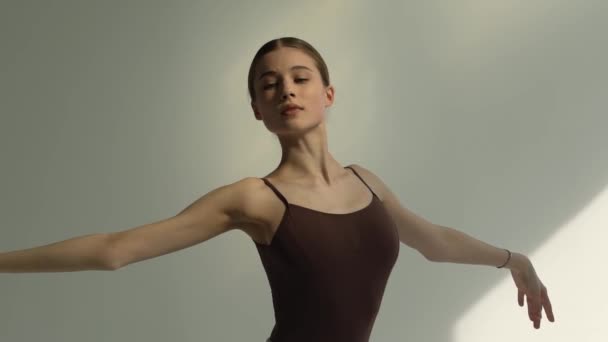 A beautiful young ballerina in the rays of bright daylight dances classical ballet and makes smooth movements with her hands. Close up. Slow motion. - Video