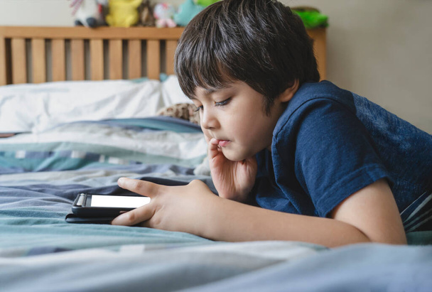 Gyerek használ tabletta a házi feladatot, Gyermek feküdt az ágyban játék digitális érintőpad a hálószobában, Fiatal fiú fekszik a mock up tablet.Otthoni oktatás, Társadalmi távolság, E-learning online oktatás - Fotó, kép