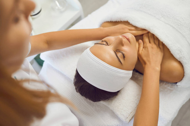 Masseur making massage of face and neck for serene woman - Foto, imagen