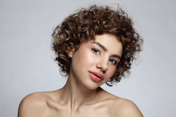 Portrait of beautiful young girl with curly hair and nude makeup - Φωτογραφία, εικόνα