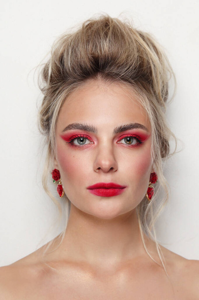 Portrait of young beautiful woman with hair bun and fancy red makeup - Φωτογραφία, εικόνα