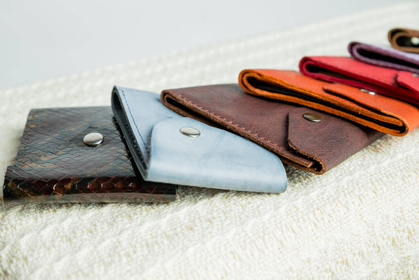 Bunte Lederbrieftaschen. Handgefertigte Brieftaschen aus Leder in verschiedenen Formen liegen auf einem beigen Textilhintergrund. Verkaufspunkt Lederwaren. - Foto, Bild