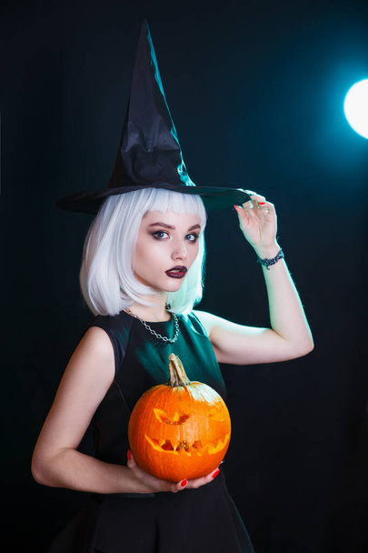 Halloween sexy witch with a carved pumpkin on dark background. Halloween party - Zdjęcie, obraz