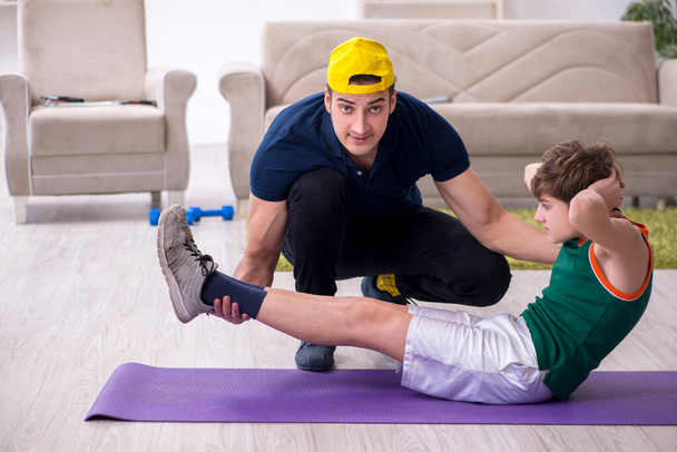 Πατέρας και γιος κάνουν αθλητικές ασκήσεις σε εσωτερικούς χώρους - Φωτογραφία, εικόνα