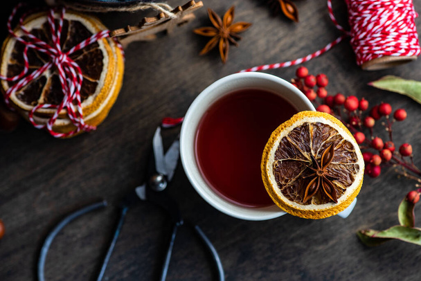 Milled or spiced wine or  Gluehwein with oranges, anise star, cinnamon and berries on rustic wooden table with copy space - Photo, Image