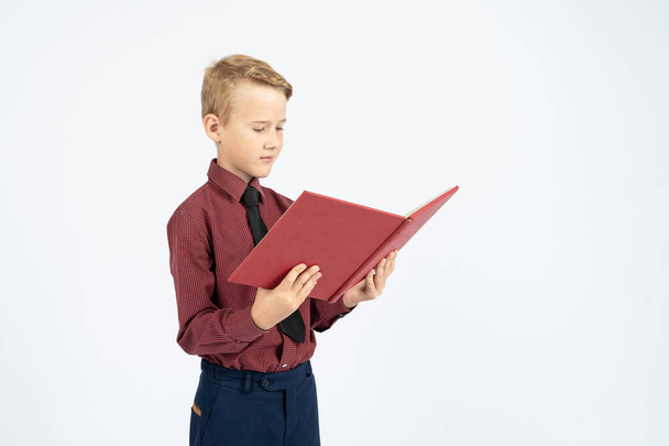 Pupil holds an open book in his hands and reads, isolated background. Education concept - Valokuva, kuva