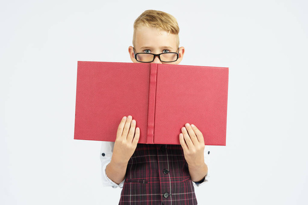 A schoolboy with glasses hides his face behind books. Isolated background. Education concept - Foto, Imagem