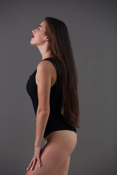 Model with beautiful skin. The girl in a black bodysuit takes a model pose. - Foto, Imagen