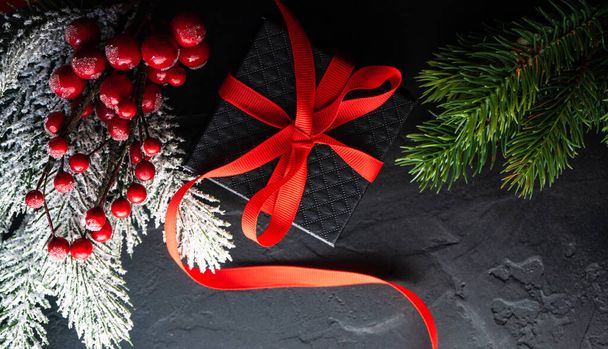Weihnachtsrahmenkonzept mit Weihnachtsbaumzweigen und rotem Feiertagsdekor auf grauem Steinhintergrund mit Kopierraum - Foto, Bild
