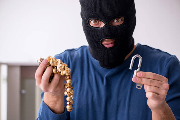 Чоловічий грабіжник краде цінні речі з дому
 - Фото, зображення