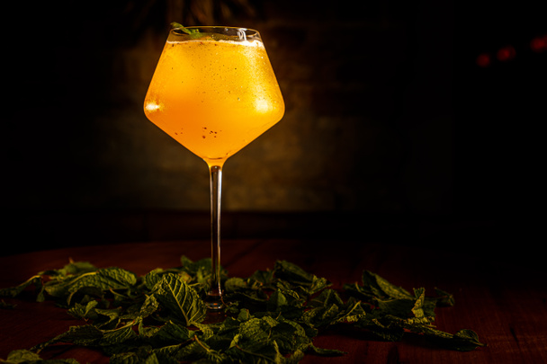 Cocktail all'arancia con menta e ghiaccio versato in un bicchiere - Foto, immagini