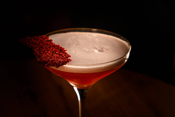A red alcoholic cocktail with foam in a glass stands on the bar - Фото, изображение