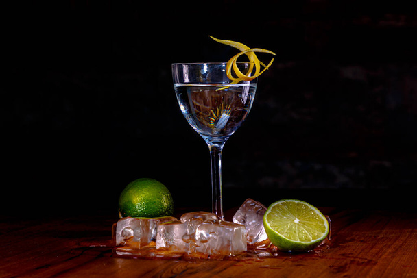 Wodka mit Eis und Zitrone im Glas auf hohem Bein steht auf der Theke - Foto, Bild