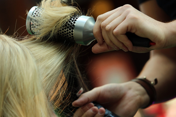 Hairdresser combing hair by hairbrush and hair dryer - 写真・画像