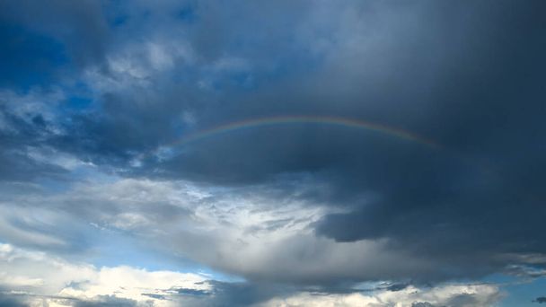 Amazing dramatic sky. Cloudy weather turning rainy. Cumulonimbus in atmosphere with rainbow. - Foto, Bild