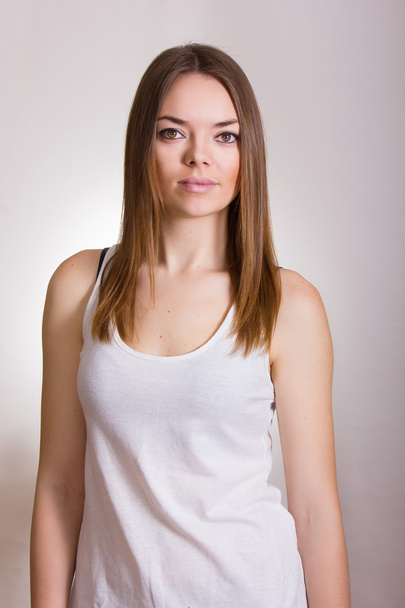 Portrait of a beautiful young woman in a white T-shirt with natural make-up and straight brown hair - 写真・画像