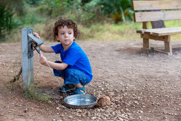 Kind öffnet Brunnen für Tiere im Park inmitten der Natur, - Foto, Bild