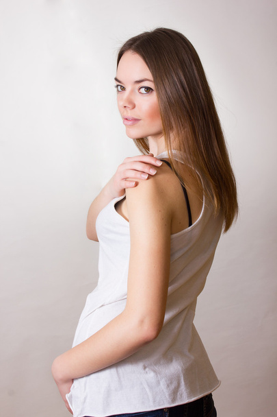 Portrait of a beautiful young woman in a white T-shirt with natural make-up and straight brown hair - Zdjęcie, obraz