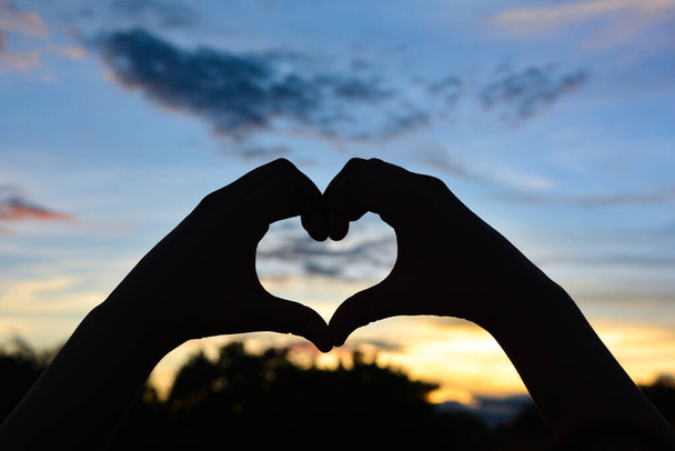 Silhouette Hand in Herzform mit Sonnenuntergang, Valentinstag-Konzept. - Foto, Bild