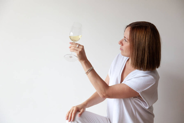 Kavkazská brunetka dívka sommelier drží sklenici bílého vína - Fotografie, Obrázek