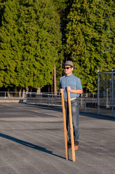 Mężczyzna w średnim wieku chodzący po drewnianych szczudłach. Vancouver BC Kanada - Zdjęcie, obraz
