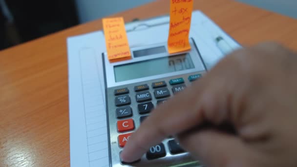 Close up footage of accountant's hand checking numbers on calculator with notes - Footage, Video