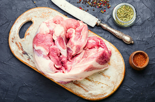 Μεγάλο κομμάτι χοιρινού κρέατος και ένα μαχαίρι κρέατος στο τραπέζι - Φωτογραφία, εικόνα