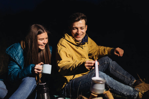 glückliches Paar trinkt nachts Tee im Wald - Foto, Bild