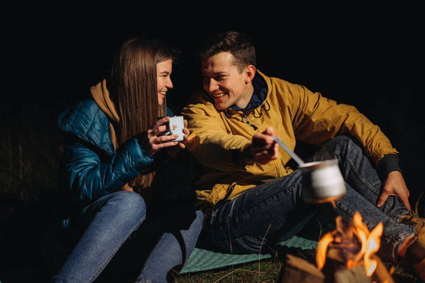 ευτυχισμένο ζευγάρι πίνοντας τσάι το βράδυ στο δάσος - Φωτογραφία, εικόνα