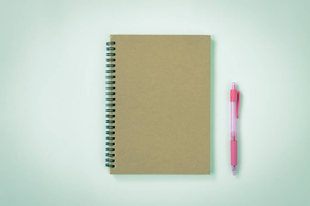 Спиральная записная книжка или весенняя записная книжка в Unlined Type и Pink Pen на фоне минимализма Blue Pastel. Спиральный макет ноутбука на центральной раме в винтажном тоне - Фото, изображение