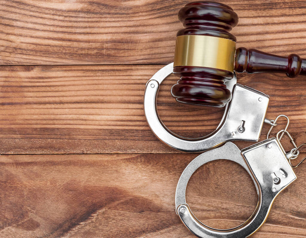 Gavel with handcuffs on wooden background. Top view. Law concept. Juristical background. - Foto, afbeelding