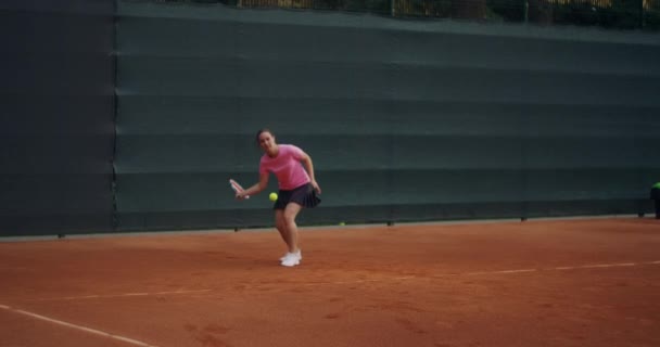 Profesyonel donanımlı kadın tenis raketiyle tenis topuna sert vuruyor. Kadın tenisçi oyun sırasında iş başında. Üzerinde markasız spor giysiler var.. - Video, Çekim