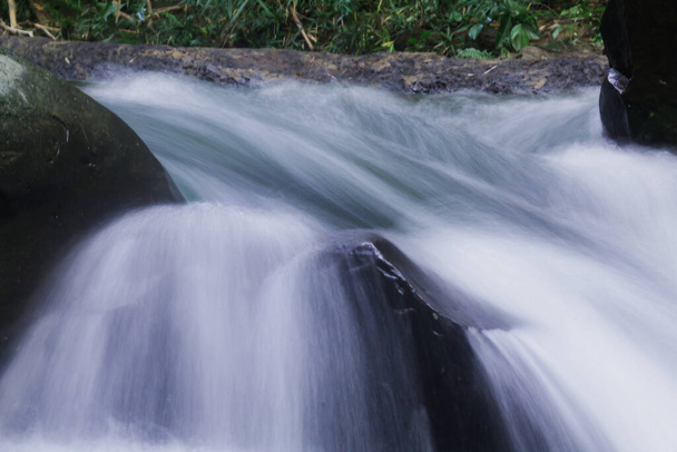 Uma cachoeira natural desce uma longa linha de um penhasco para um vale de aspersão. - Foto, Imagem